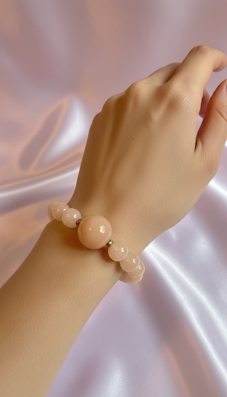 Beige beaded bracelet on a light pink fabric background
