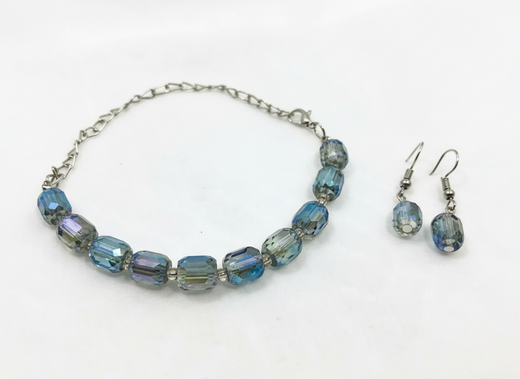 Bracelet et boucles d'oreilles en cristal de verre gris fumé et bleu, ornés de perles, avec une chaîne métallique argentée.