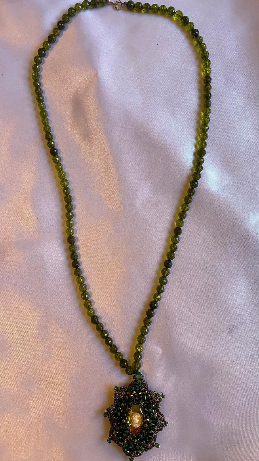 Green beaded necklace with a pendant on a light background