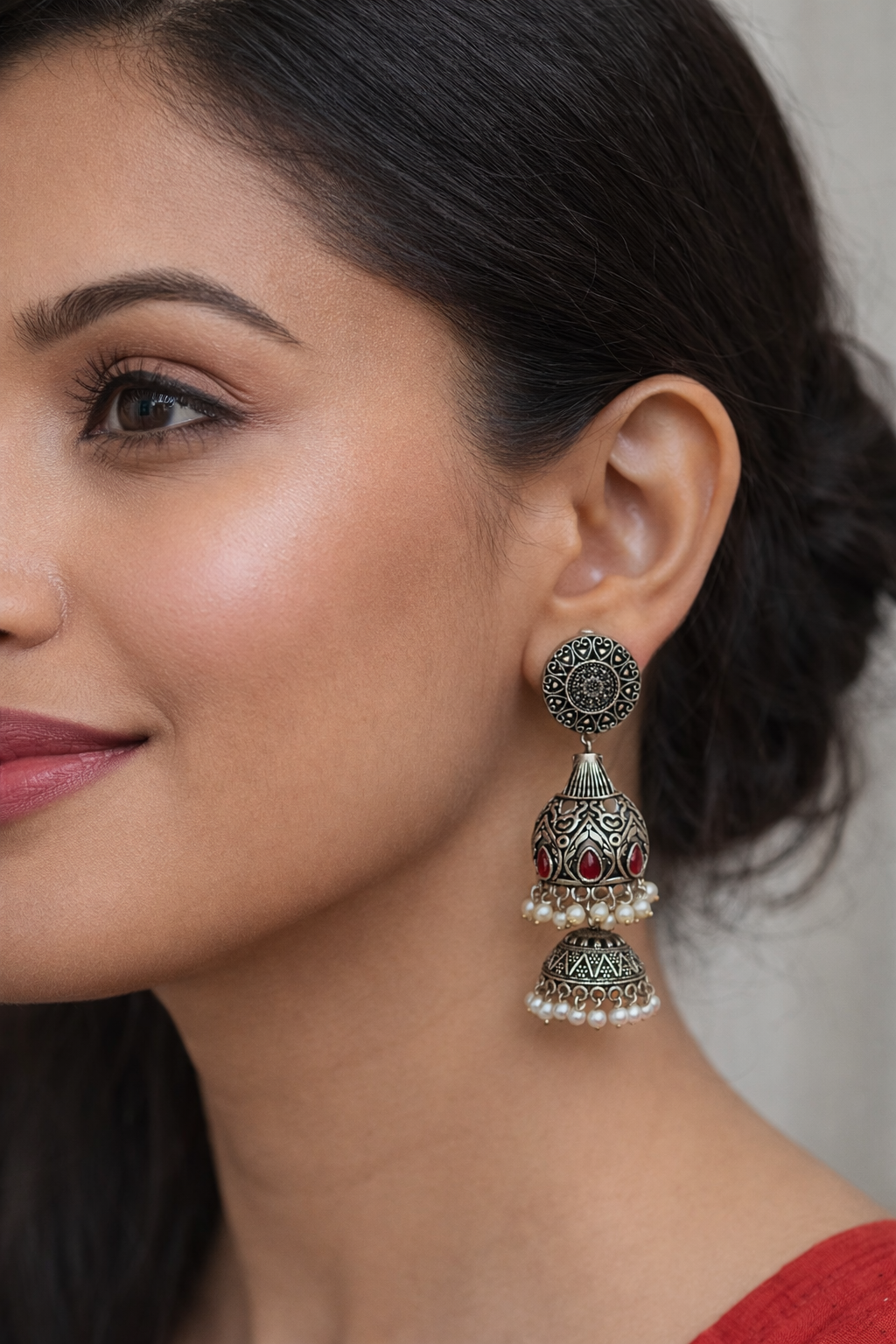 Boucles d'oreilles argentées en métal gravé, ornées de pierres rouges et d'une bordure en perle blanche.