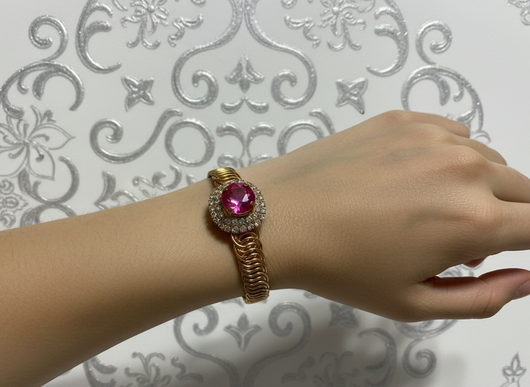 Bracelet orné d'une pierre centrale rose et de pierres blanches, avec bracelet en métal doré