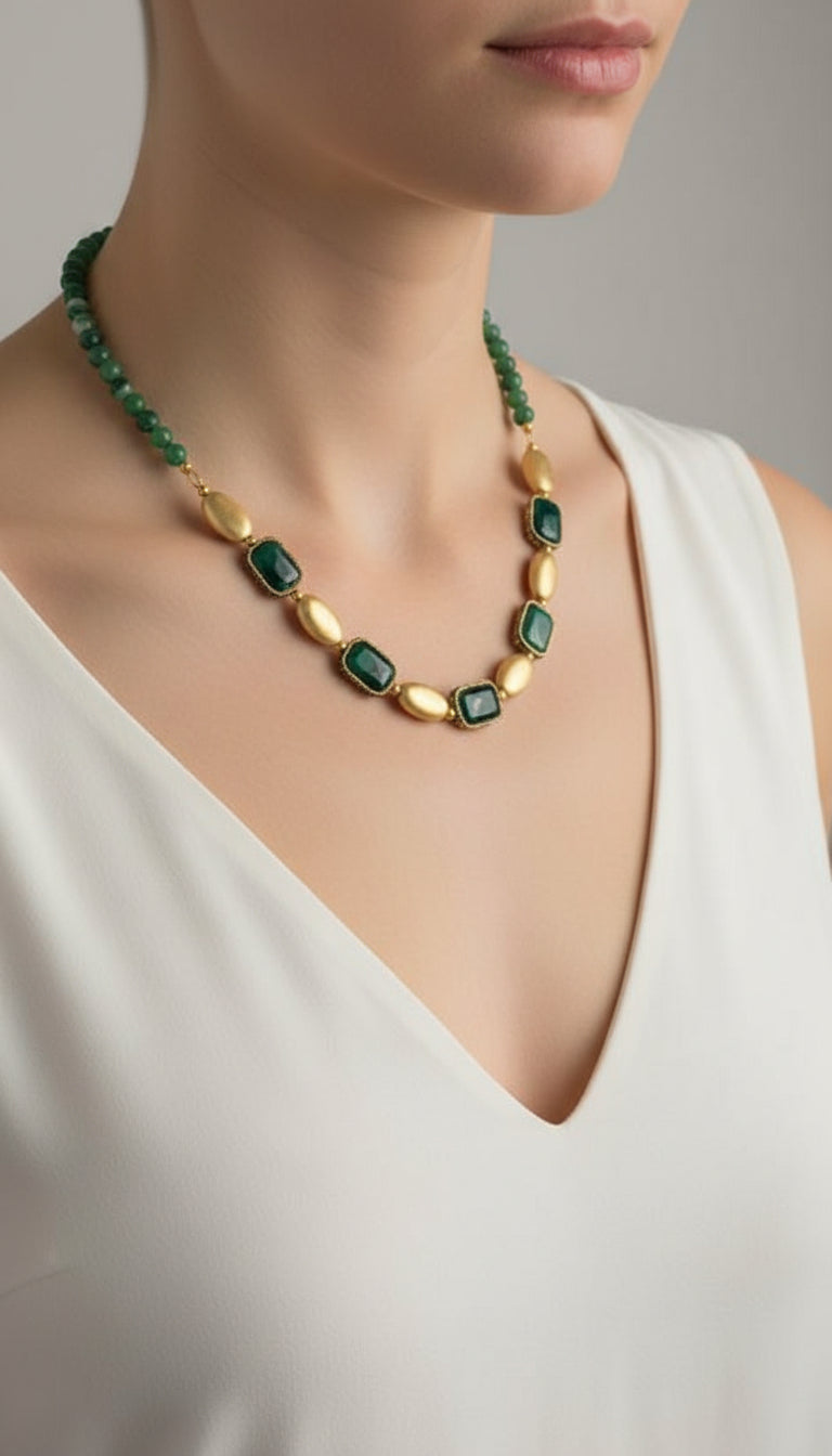 Necklace with green beads and gold accents on a light purple background