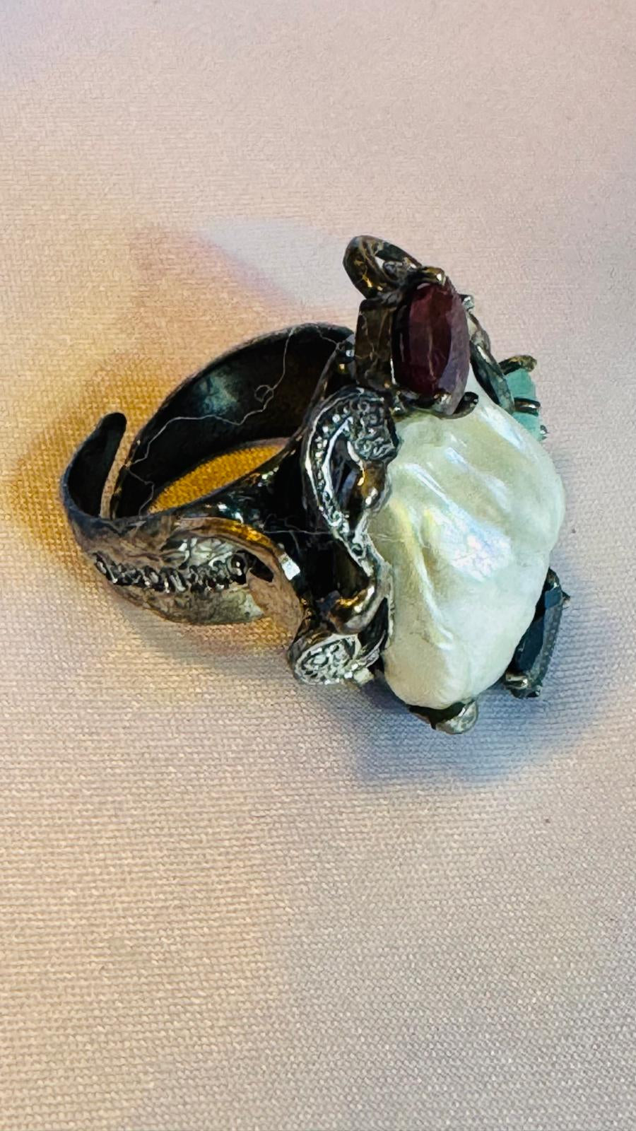 Decorative ring with a central pearl and garnet stone