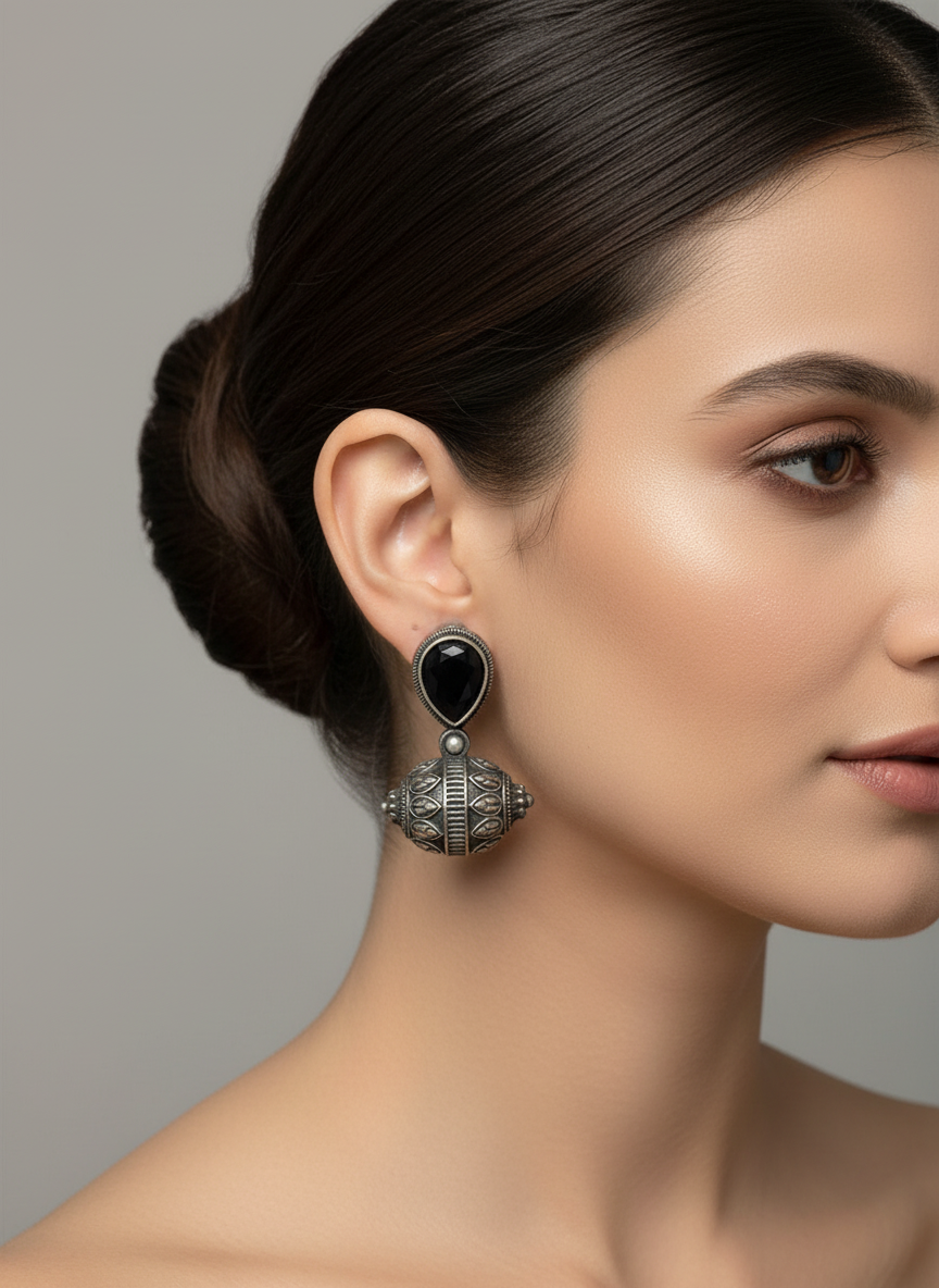 Woman wearing a black and silver earring against a neutral background